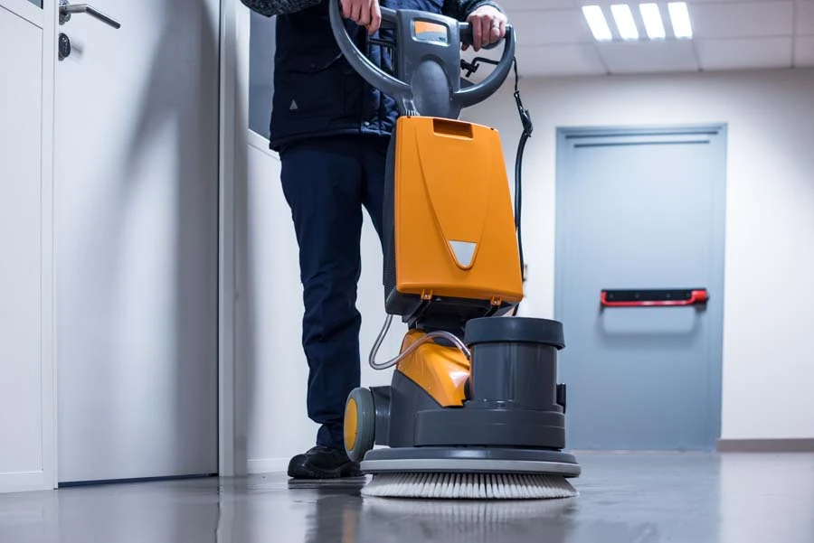 Nettoyage professionnel d'un sol carrelé dans un environnement intérieur avec un agent d'entretien utilisant une monobrosse